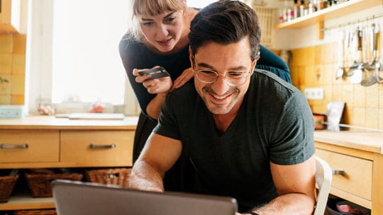Woman leaning over man’s shoulder to look at computer